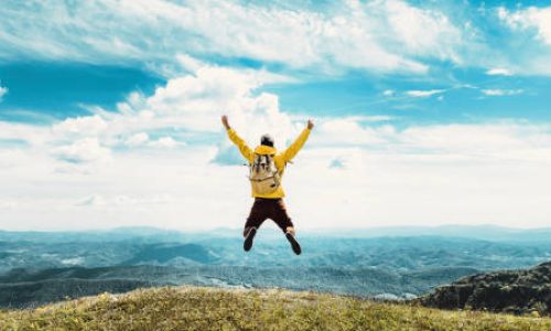 Happy man with open arms standing on the top of mountain - Hiker with backpack celebrating success outdoor - People, success and sport concept